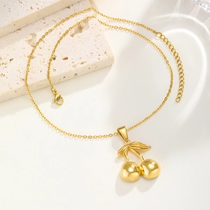 Collier avec pendentif cerise doré élégamment présenté sur une pierre texturée minimaliste