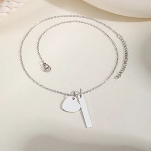 Macro detail of silver stainless steel heart and bar pendants with delicate link chain