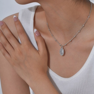Detailopname van zilveren ketting met kraaltjes en ovaal Maria-medaillon voor dames