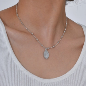 Macro-detail van de zilveren Maagd Maria-hanger aan een slangenketting voor dames