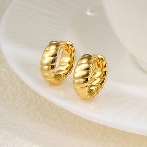 Vue macro de boucles d'oreilles créoles torsadées 14K sur plateau en céramique