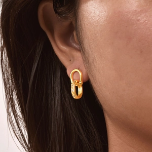 Orecchini ovali intrecciati placcati oro con intarsio di zirconi indossati da una modella