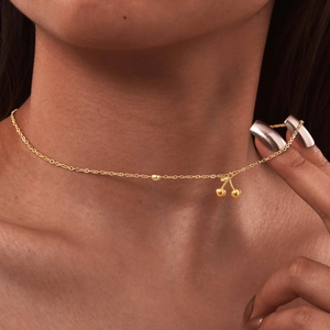 Close-up of a gold cherry pendant necklace with zircon stone on elegant model skin