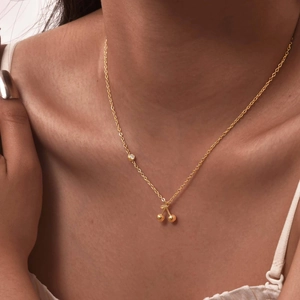 Elegant gold stainless steel cherry pendant necklace with zircon accent on a female neck