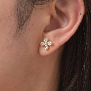 Macro view of gold flower earrings with marquise-cut clear stones on model's ear
