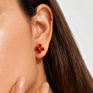 Elegant gold flower earrings with four red pear-shaped stones worn by a model