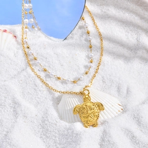 Collier double rang doré tortue marine avec perles et pendentif étoile de mer sur sable