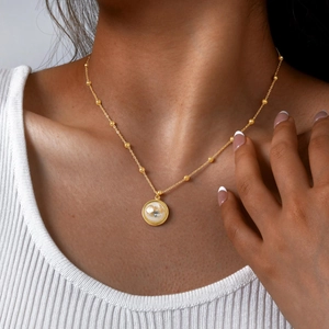 Close-up of ocean-themed resin pendant necklace with starfish and shell details on model