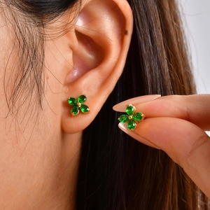 Detailed macro view of green zircon four-leaf clover stud earrings in gold plating