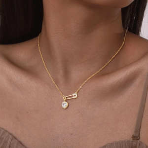 Gold paperclip necklace with heart pendant and sparkling zircon stones on female model