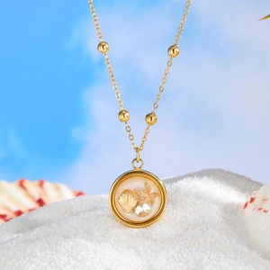 Golden ocean theme necklace with shell and starfish pendant on white beach sand