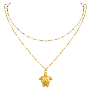 Collier double couche doré avec pendentif tortue et perles blanches sur fond blanc épuré