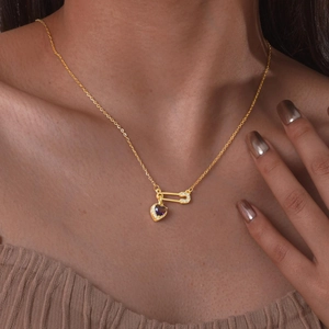 Paperclip necklace with gold heart pendant and purple gemstone on model collarbone