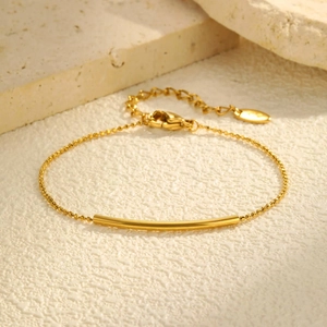 Bracelet perles en or 18 carats avec tube poli sur un fond en pierre naturelle