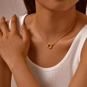 Detailaufnahme einer goldfarbenen Perlenkette mit Federringverschluss an einem Model