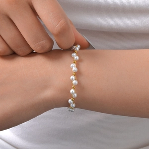 Bracelet élégant en acier inoxydable 18k et perles blanches porté sur un poignet