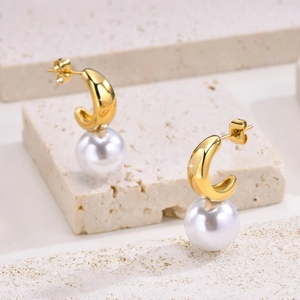 Détails macro de boucles d'oreilles perles dorées en C sur pierre de travertin texturée