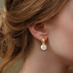 Boucles d'oreilles créoles dorées avec perles pour femmes portées dans un style épuré