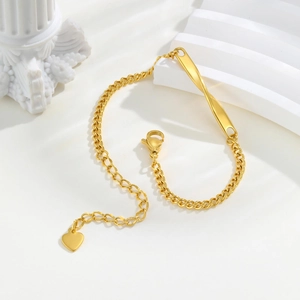 Détail d'un bracelet Mobius doré avec pendentif en cœur sur un support de colonne blanche
