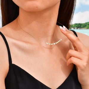 Minimalist gold chain necklace with white shell beads on model at sunlit beach