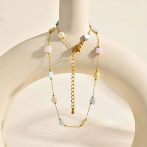 Détail du collier doré avec fleurs en émail macaron, fermoir mousqueton et chaînette