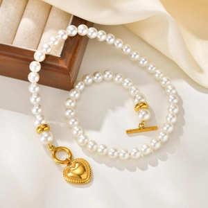 Elegante Perlenkette mit goldenem Herzanhänger und Vintage OT-Verschluss auf Seide