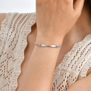Bracelet Mobius argenté élégant pour femme au poignet sur un fond en maille douce