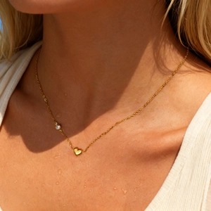 Goldene Herz- und Zirkonia-Halskette am Schlüsselbein mit erfrischenden Wassertropfen