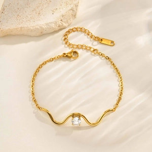Détail du bracelet vague doré avec zircon rond et gravure K18 sur le fermoir