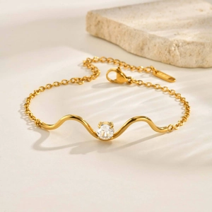 Détail macro du bracelet en acier doré avec design ondulé et oxyde de zirconium blanc