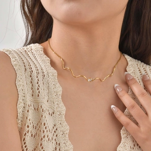 Détail du bracelet ondulé en acier doré avec zircon sur le poignet d'une femme