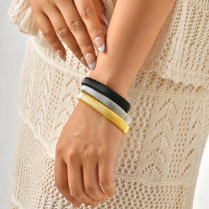 Set di tre bracciali elastici testurizzati in oro, argento e nero indossati sul polso