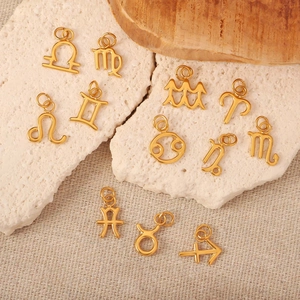 Vista de doce colgantes dorados de los signos del zodiaco sobre piedra blanca y lino