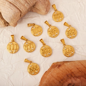Macro shot of gold numbered round pendants with sparkling crystals on white textured fabric