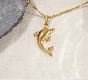 Macro detail van de gepolijste 24k vergulde dolfijn hanger aan een fijne ketting