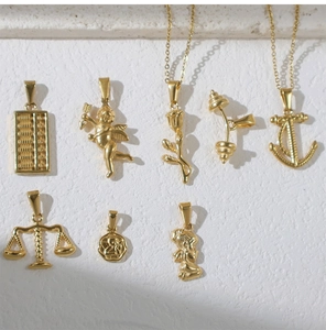 Detailansicht verschiedener goldener Anhänger wie Anker und Rose auf Marmorhintergrund