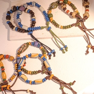 Dettaglio di bracciali con perline in ceramica colorata e cordini in stile etnico