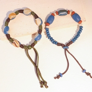 Dettaglio di bracciali etnici in ceramica con perline, nodi fatti a mano e trama marmorea