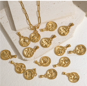 Gros plan des pendentifs zodiaque dorés 18 carats sur un fond en pierre blanche