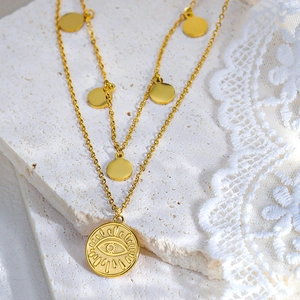 Dettaglio della collana a due strati dorata con ciondolo occhio e piccoli dischi