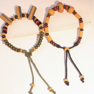 Dettaglio di braccialetti etnici in perle di ceramica fatti a mano con lacci intrecciati