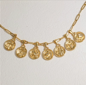 Détail d'une chaîne trombone plaquée or 18 carats avec plusieurs pendentifs zodiaque