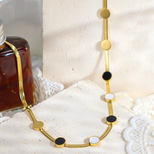 Dettaglio della collana a catena serpente dorata con ciondoli in smalto bianco e nero