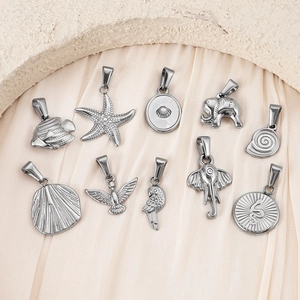 Macro detail of silver stainless steel pendants featuring stars, fish, and elephant motifs