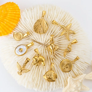 Detailed macro view of 24k gold-plated stainless steel charms on a white coral background