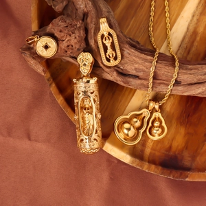 Close-up of gold gourd and Buddhist pendants displayed on natural wood with silk backdrop