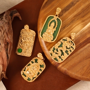Gold stainless steel Buddha and Dragon pendants with green jade-like accents on wood