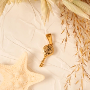 Detailed macro view of gold-plated key pendant with religious relief on textured paper