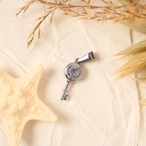 Macro detail of silver key pendant with St. Benedict medal relief on warm paper