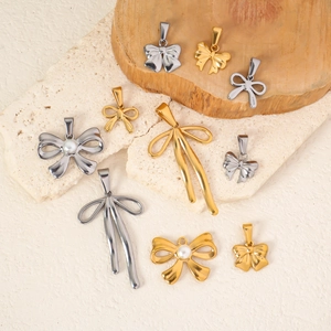 Colliers nœud en or 24 carats et argent avec perles sur pierre texturée et bois blanc